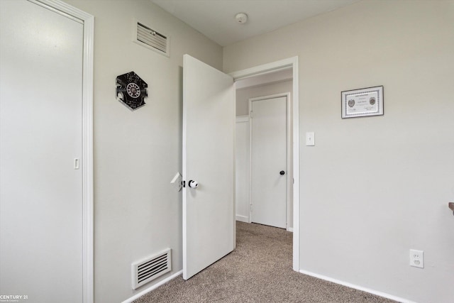 hallway featuring baseboards, carpet flooring, and visible vents