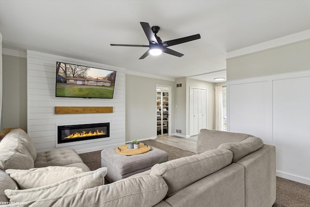 living area with baseboards, a fireplace, and a ceiling fan