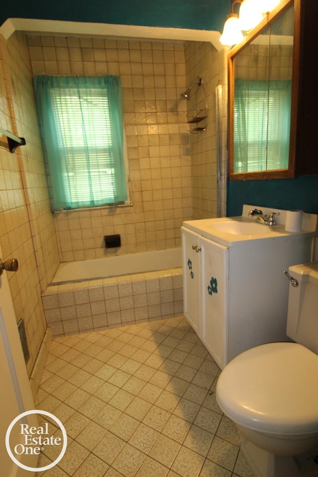 bathroom featuring tile patterned flooring, tiled shower / bath combo, toilet, and vanity