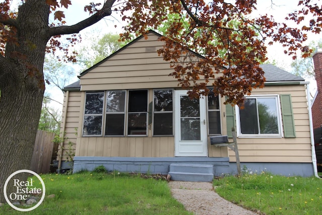 bungalow-style home featuring a front lawn, fence, and entry steps