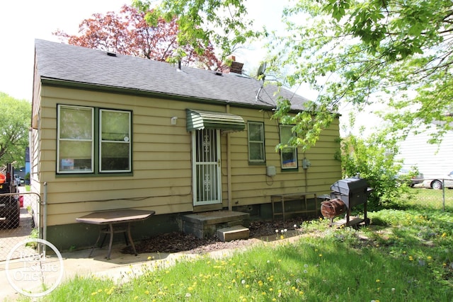 back of property with roof with shingles, fence, and a chimney