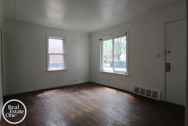 spare room featuring baseboards, dark wood-style floors, and visible vents