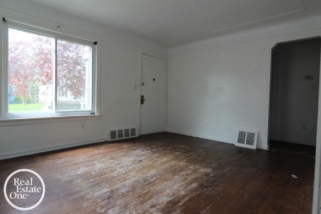 unfurnished room featuring visible vents, wood-type flooring, and a wealth of natural light