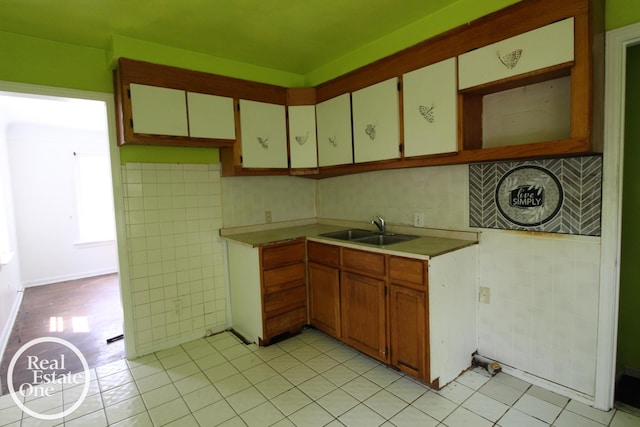 kitchen featuring light countertops, a sink, light tile patterned floors, and tile walls