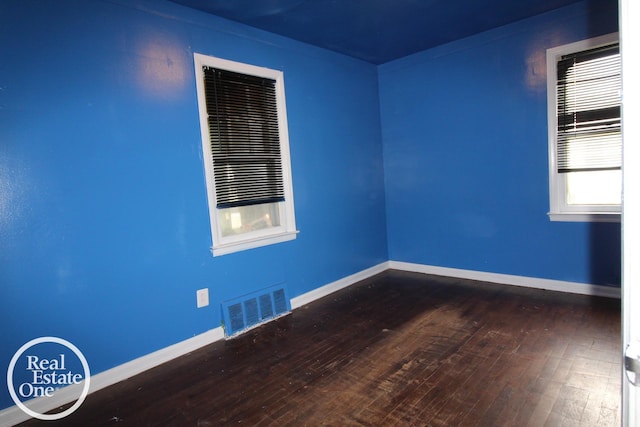 unfurnished room with baseboards, hardwood / wood-style flooring, and visible vents