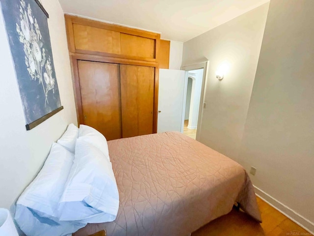 bedroom with baseboards, a closet, and wood finished floors