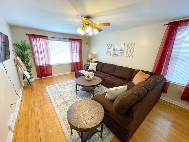 living area featuring baseboards, ceiling fan, and light wood-type flooring