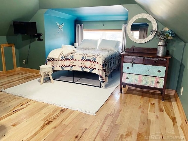 bedroom with baseboards, vaulted ceiling, and wood finished floors
