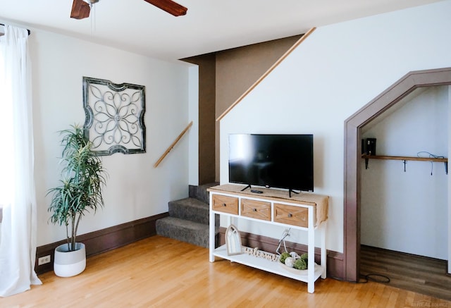 living area with stairs, ceiling fan, and wood finished floors