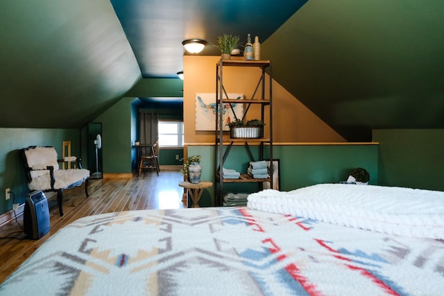 bedroom with baseboards, wood finished floors, and lofted ceiling