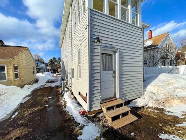 view of snowy exterior with fence and entry steps