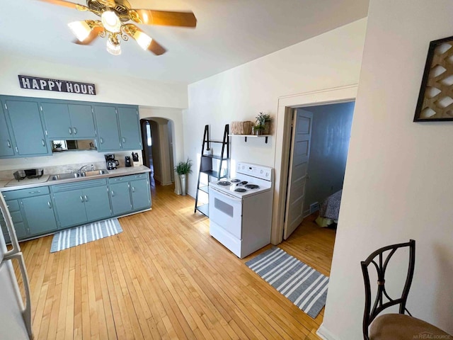 kitchen featuring a ceiling fan, blue cabinetry, arched walkways, a sink, and white range with electric stovetop