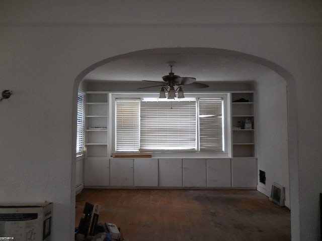 unfurnished room featuring arched walkways, a ceiling fan, and wood finished floors