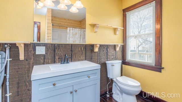bathroom featuring vanity, an inviting chandelier, wood finished floors, toilet, and tile walls