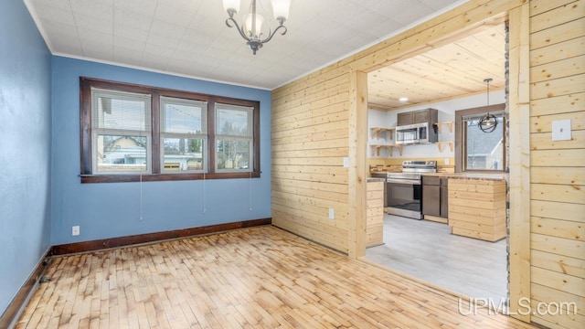 interior space featuring an inviting chandelier, light wood-style flooring, crown molding, and baseboards
