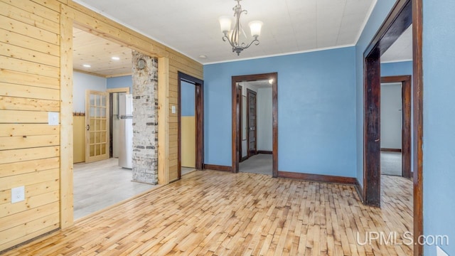 unfurnished room featuring crown molding, baseboards, a notable chandelier, and wood finished floors