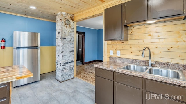 kitchen featuring freestanding refrigerator, wooden ceiling, a sink, and light countertops