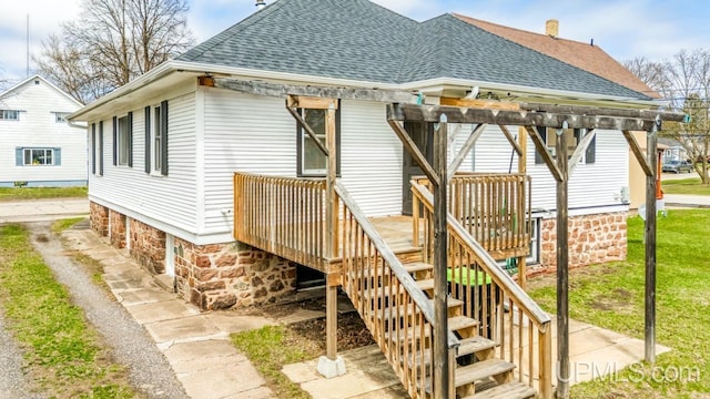 back of property with a deck, a chimney, a shingled roof, a yard, and stairway