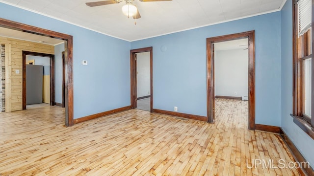 spare room featuring crown molding, a ceiling fan, baseboards, and wood finished floors