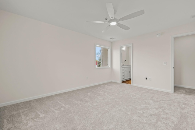 unfurnished bedroom with visible vents, light carpet, baseboards, ceiling fan, and ensuite bath