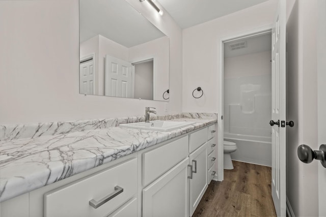 bathroom featuring visible vents, wood finished floors, vanity, toilet, and bathing tub / shower combination