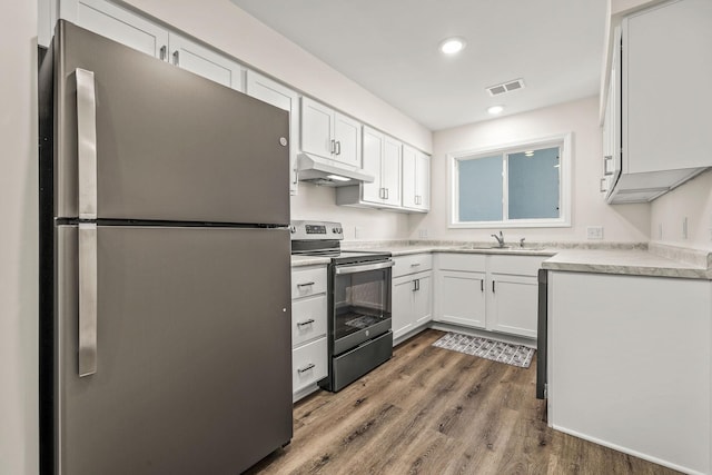 kitchen featuring white cabinets, stainless steel appliances, wood finished floors, and under cabinet range hood
