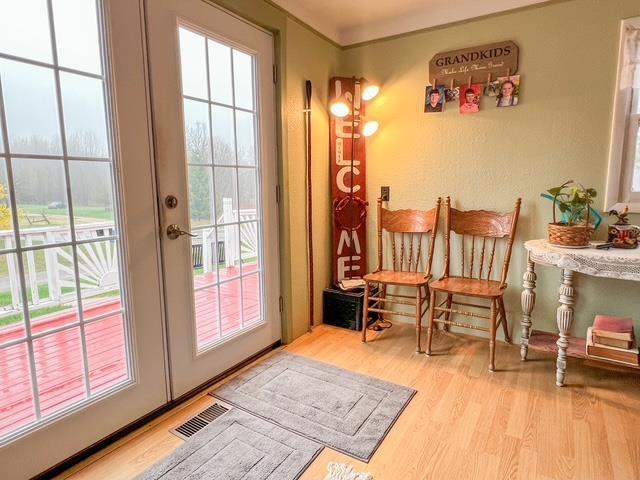 doorway to outside featuring french doors, wood finished floors, visible vents, and a healthy amount of sunlight