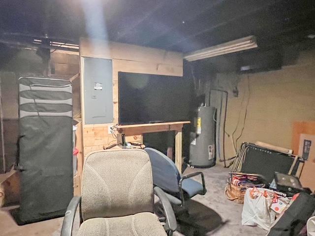 misc room featuring concrete flooring, water heater, and electric panel