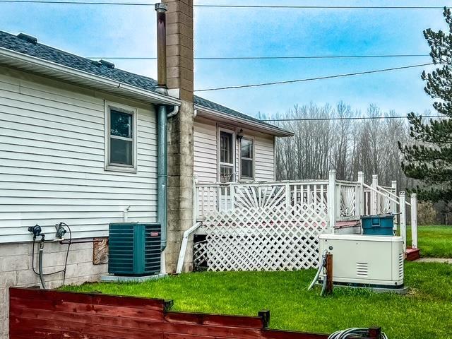 view of property exterior featuring a wooden deck, central AC unit, a chimney, and a yard