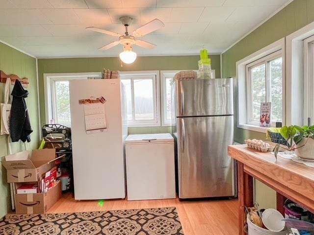 kitchen featuring light wood-type flooring, freestanding refrigerator, fridge, and ornamental molding