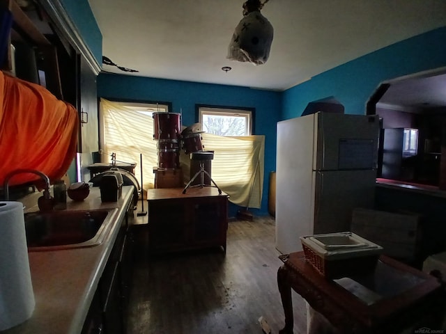 kitchen with a sink, arched walkways, wood finished floors, and freestanding refrigerator
