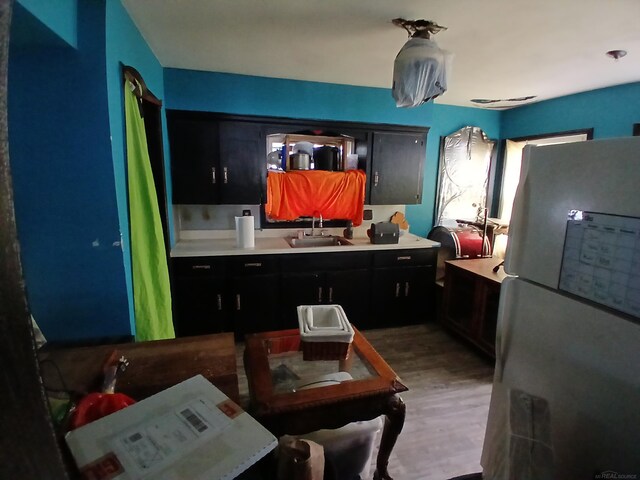 kitchen featuring a sink, light countertops, freestanding refrigerator, and light wood finished floors