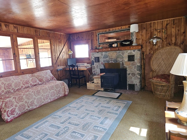 living area featuring carpet flooring, wooden walls, a wood stove, and wooden ceiling