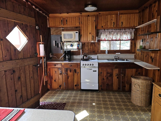kitchen with a sink, wood walls, dark floors, and white appliances