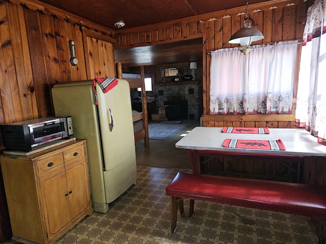 kitchen featuring wooden walls, brown cabinets, dark floors, decorative light fixtures, and stainless steel microwave
