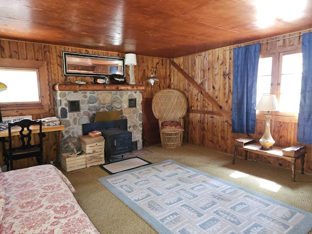 carpeted living area with a wood stove, wooden walls, and wooden ceiling