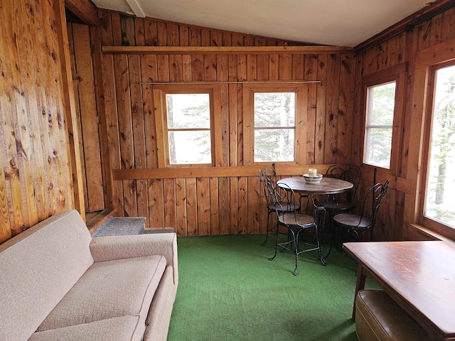 dining space featuring wood walls, carpet, and lofted ceiling