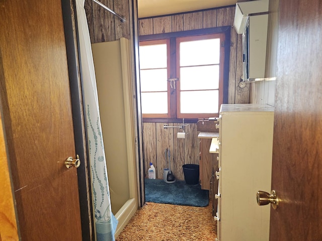 bathroom featuring a shower with shower curtain and wooden walls