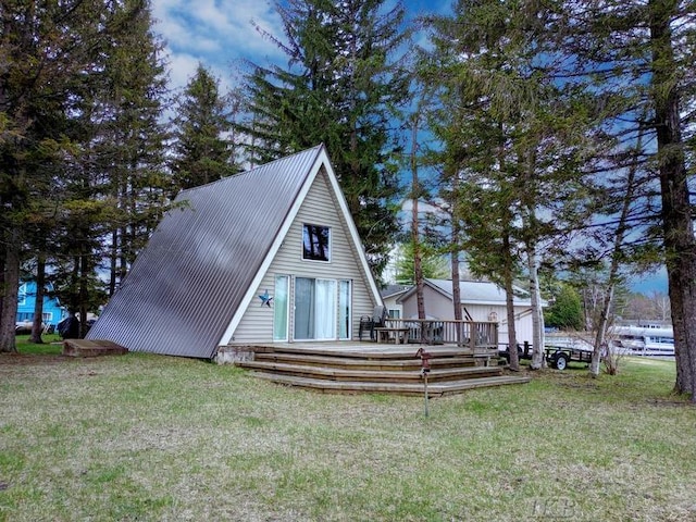 rear view of property with a lawn, a wooden deck, and metal roof