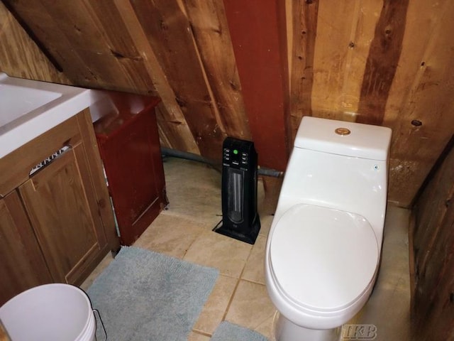 bathroom featuring vanity, tile patterned floors, wooden walls, and toilet