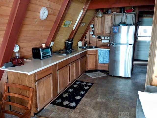kitchen with wood walls, a toaster, brown cabinets, a sink, and appliances with stainless steel finishes
