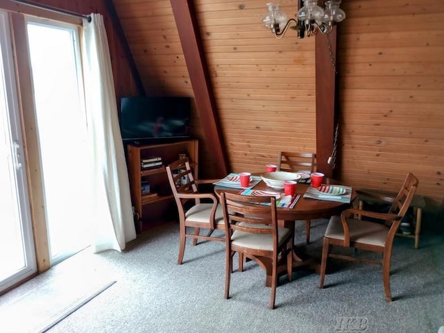 carpeted dining area with a chandelier, wooden walls, and wooden ceiling