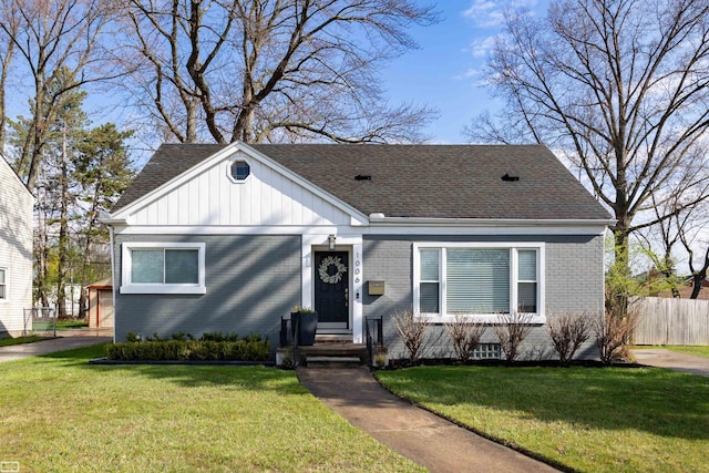 bungalow-style home with fence, a shingled roof, brick siding, board and batten siding, and a front yard
