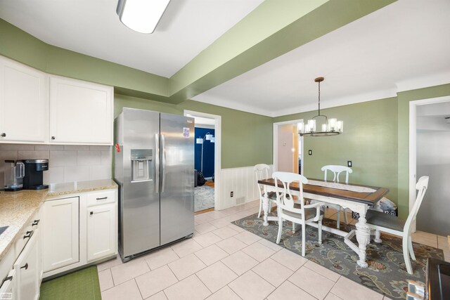 kitchen with hanging light fixtures, a wainscoted wall, white cabinets, a chandelier, and stainless steel fridge