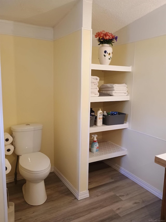 bathroom with baseboards, wood finished floors, and toilet