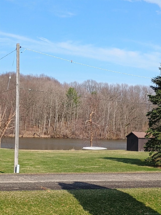 view of home's community featuring an outbuilding, a water view, and a yard