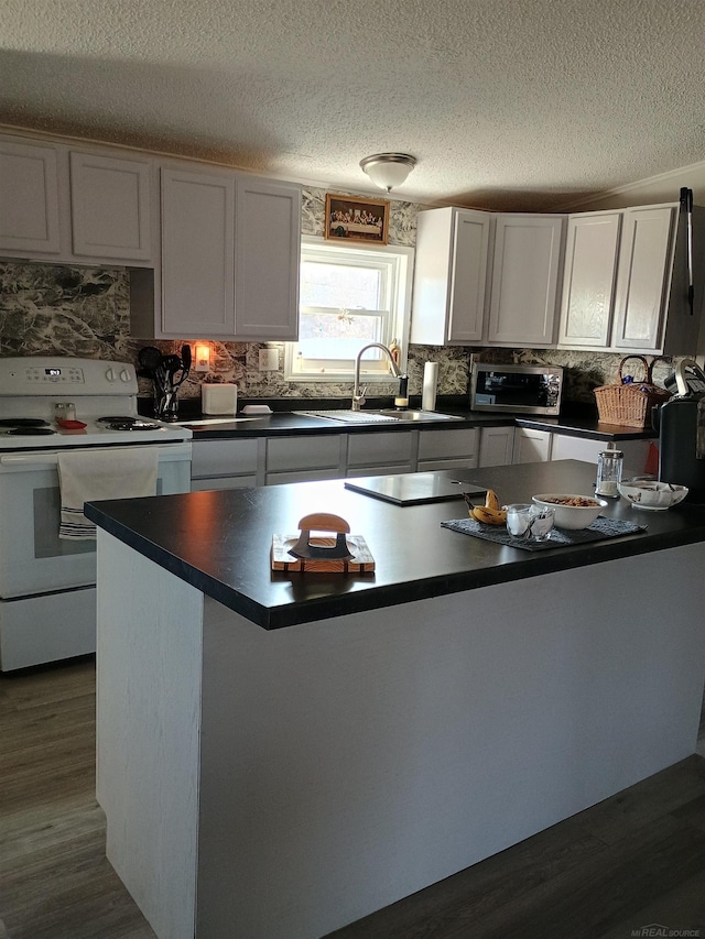 kitchen featuring white electric range oven, dark countertops, a sink, a textured ceiling, and tasteful backsplash