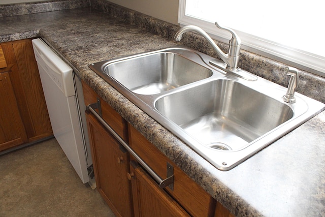 room details with a sink, dishwasher, brown cabinets, and dark countertops