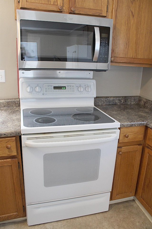 kitchen with stainless steel microwave, brown cabinetry, and electric stove