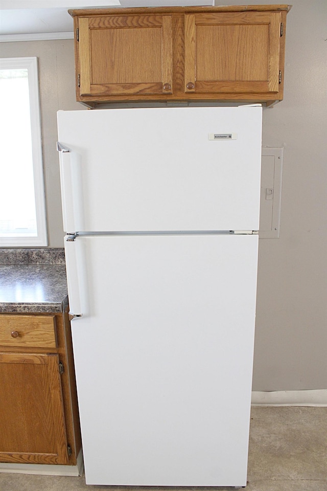 room details with freestanding refrigerator, brown cabinets, dark countertops, and baseboards